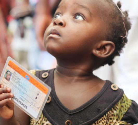 Crédits Photo: MONUSCO / Myriam Asmani. Une petite fille tenant une carte de vote lors des élections de 2011 en République démocratique du Congo (RDC).